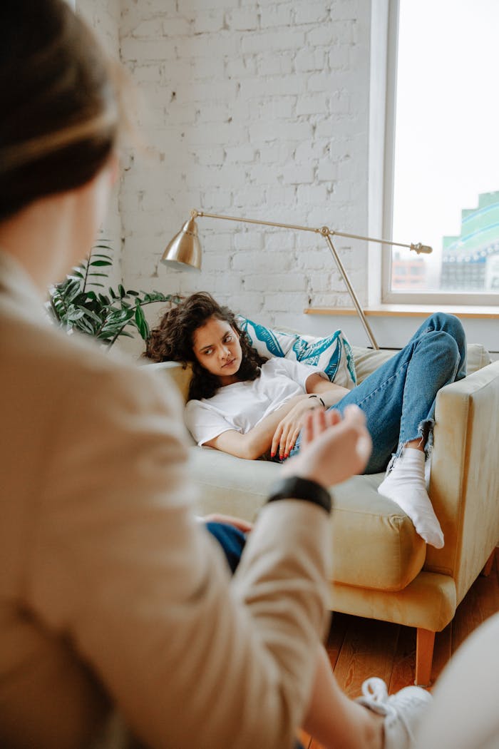 The Art of Drawing Readers In: Your attractive post title goes here A therapist converses with a young adult on a sofa, focusing on mental health.