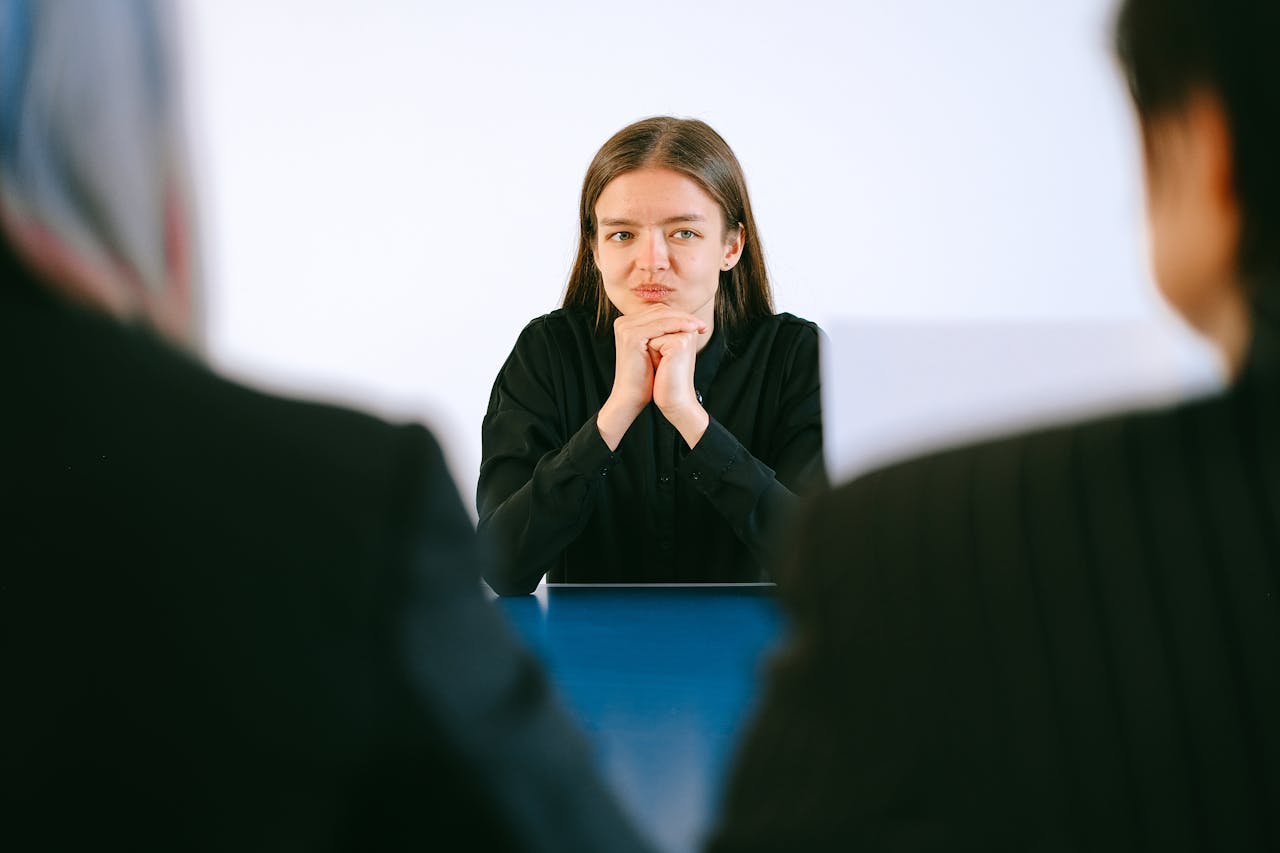 Crafting Captivating Headlines: Your awesome post title goes here A woman in a job interview facing two people at an office table, focusing intently.