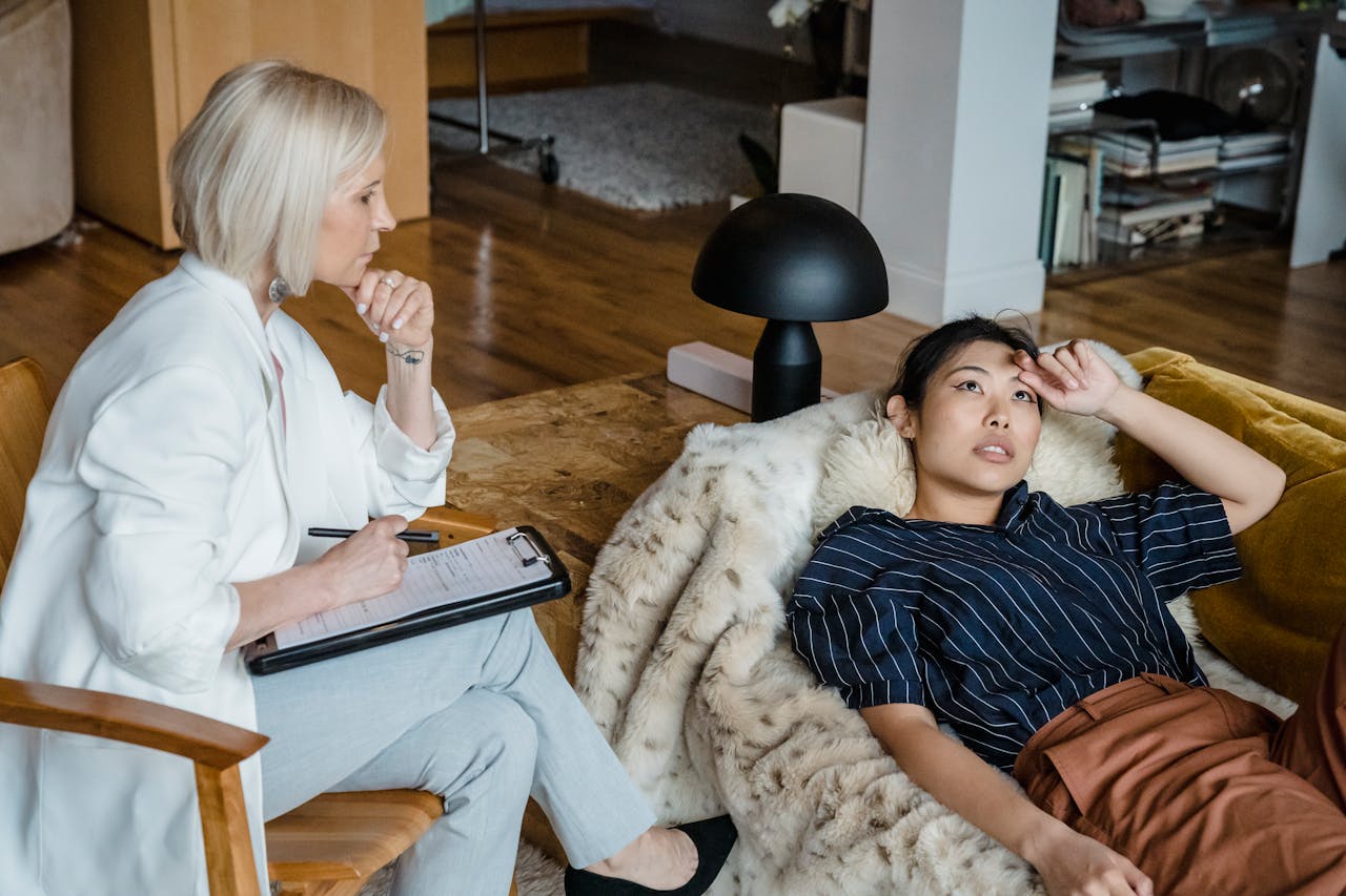 Services Psychologist listens attentively to a stressed young woman during therapy session.